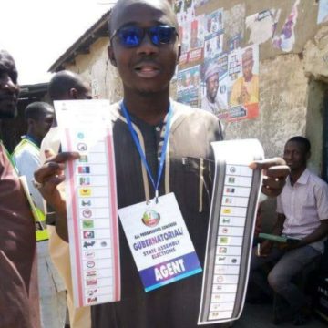 Kano APC agent displays his thump printed papers after voting for NNPP
